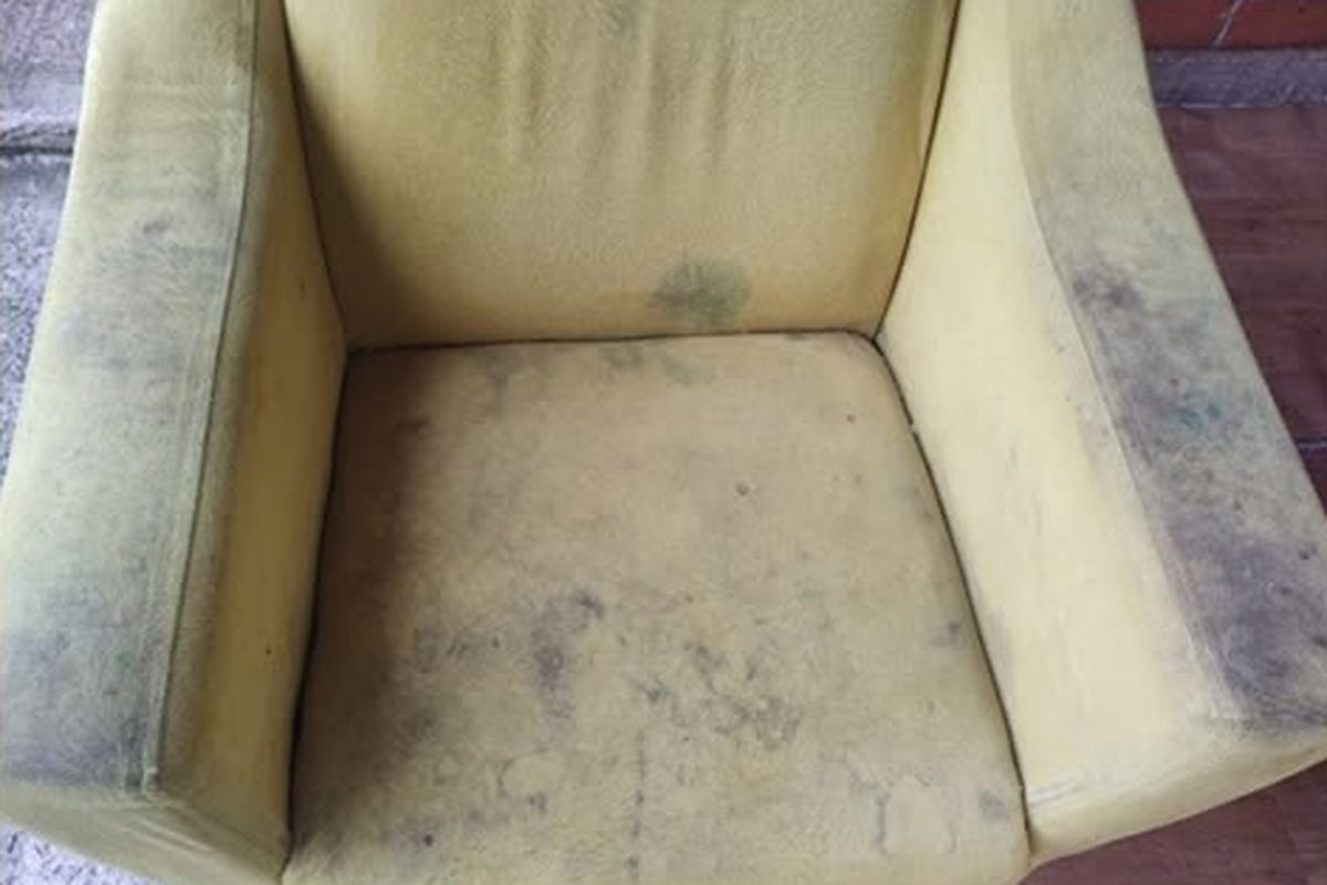 Assento e braço de um cadeirão de tecido amarelo com nódoas escuras, antes da limpeza